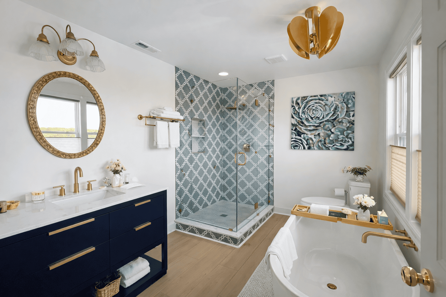 Elegant spa-style bathroom at Laurel Haven Estate in Lancaster SC featuring a freestanding soaking tub with bath tray, navy vanity with gold fixtures, glass walk-in shower, and bright natural light in a luxury bed and breakfast suite